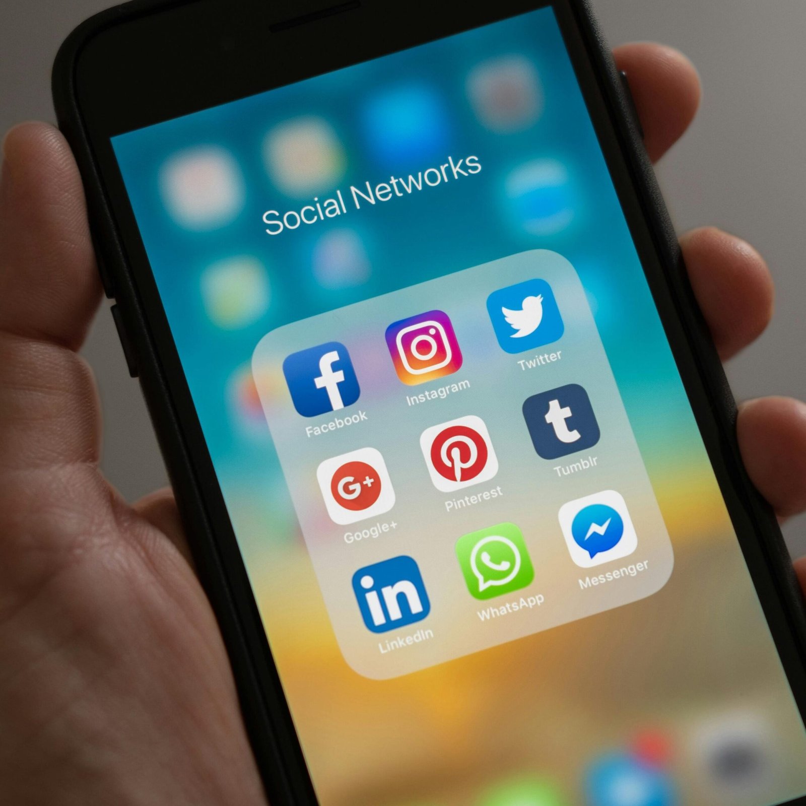 A smartphone displaying various social media icons held in a hand, showcasing modern communication apps.