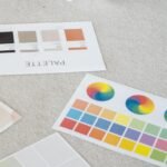 Young woman reviews color palettes for design project on laptop, sitting indoors.